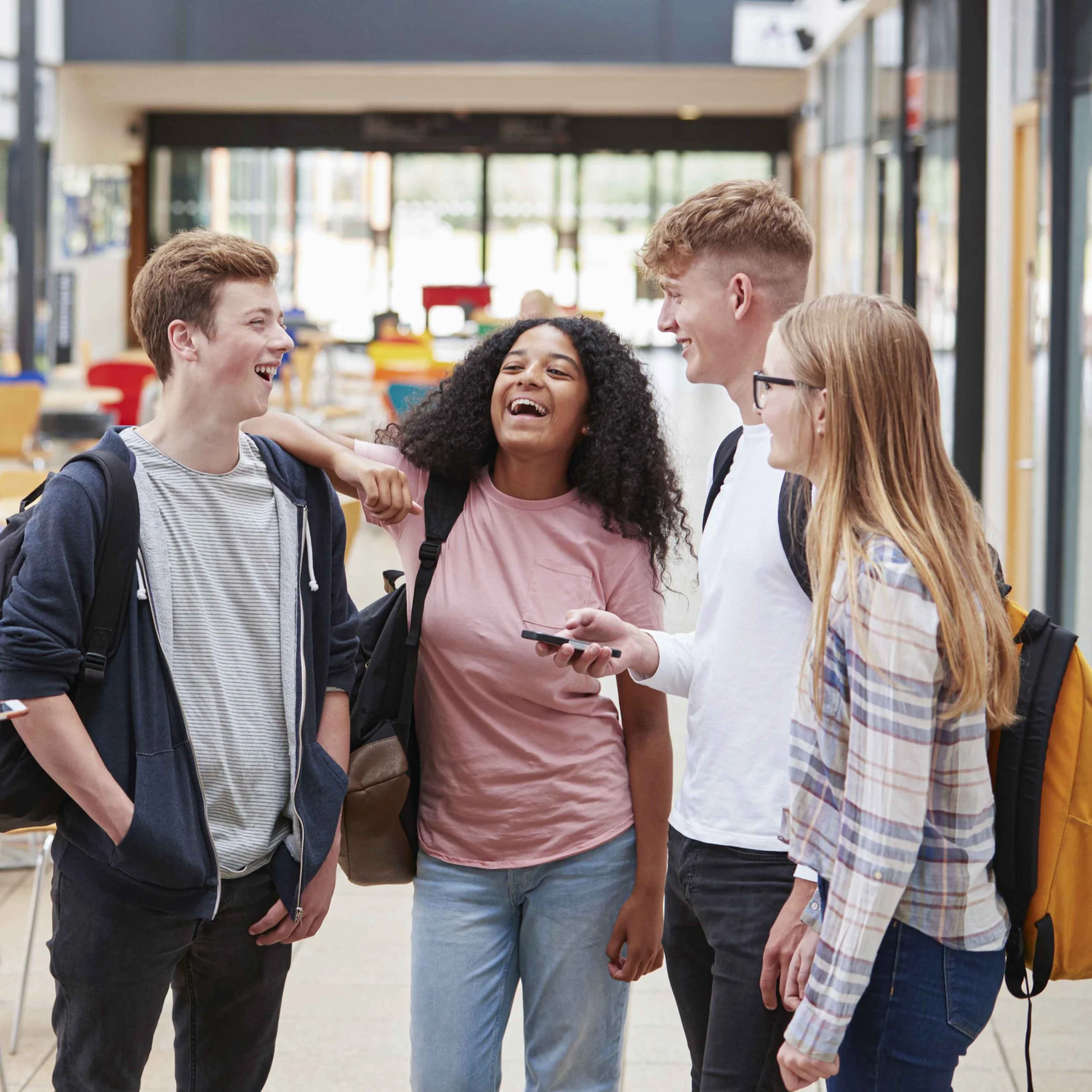 Eine Gruppe aus vier Teenagern steht zusammen und lacht